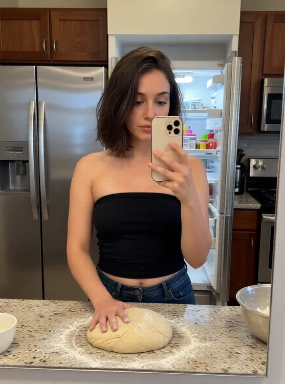Luna - Kitchen counter; she kneads dough, mirror selfie from fridge, eyes on dough.